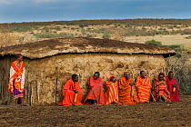 Maasai village elders with drinking gords and Maasai woman in front of hut, Maasai village, Kenya. September 2006.
