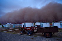 Sand storm rolling in towards lodges on farm, Inner Mongolia, China