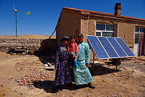 Mongolian shepherd Manduhu, left, with his brother in law and nephew in front of his house, wind mill and solar panels for energy, Inner Mongolia, China. May 2016