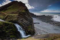 A small waterfall on the coast at the side of St Catherine&#39;s Tor, near Hartland Quay, Devon, UK, March
