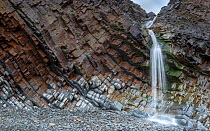 A small waterfall at Sandy Mouth beach, near Bude, Cornwall, UK, March. The rocks are steeply dipping Carboniferous age, sandstone and shale (Culm Measures).