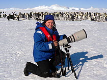 Portrait of wildlife photographer Sue Flood photographing Emperor penguins (Aptenodytes forsteri) with Canon camera at Snow Hill Island rookery, Weddell Sea, Antarctica. October 2008.