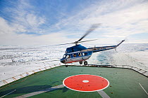 Helicopter taking off from Russian icebreaker Kapitan Khlebnikov in the Weddell Sea en route to Snow Hill island emperor penguin colony. Antarctica.