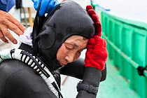 Ama diver putting on wetsuit in preparation for work underwater. Futo Harbour, Izu Peninsula, Shizuoka Prefecture, Japan. June 2010.
