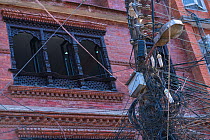 Cables and telegraph pole with building in background, Kathmandu City, Kathmandu Valley, Nepal. February 2018.