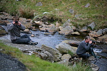 Photographer Oliver Hellowell using a bridge camera with Mike O&#39;Carrol taking picture by stream, England, UK, May 2010.