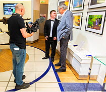 Photographers Oliver Hellowell and Ken Jenkins (Tennessee based photographer) being filmed at their joint exhibition at the T5 Gallery, Heathrow Airport, England, UK. July.