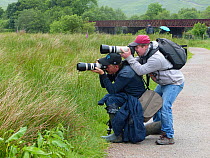 Photographer Oliver Hellowell taking pictures, balancing the camera on the head of photographer Mike O&#39;Carroll, England, UK. June 2017.