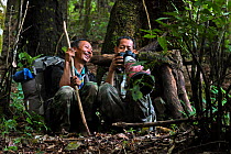 Two guides looking at photographs taken on camera whilst sitting on forest floor. Wuliangshan Nature Reserve, Jingdong, Yunnan Province, China. October 2017.