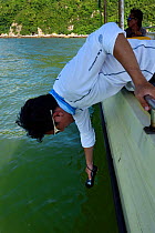 Scientist measuring water data whilst monitoring Indo-Pacific humpback dolphin (Sousa chinensis) Tai O, Lantau Island, Hong Kong, China. June, 2016.