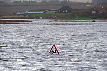 View across Cley Marshes from West Bank with Coastguards road sign submerged in flood waters, North Norfolk, England, UK. January 13th 2017.