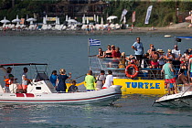 Tourists on boats surrounding Loggerhead sea turtle (Caretta caretta) Zakynthos, Greece, August.