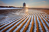 Sand patterns with ice between ripples of the sand, front of Burnham-on-Sea Lighthouse in winter, Somerset, England, UK, January.. January 2010