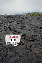 Old trail marker sign buried in fresh lava flow, west of Kalapana, Puna, Hawaiian Islands, USA, December 2011.