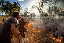 Cameraman Murray Fredericks films a wildfire triggered by lightning for Storm Chasing programme in Northern Australia for BBC Wonders of The Monsoon. Western Australia. December 2013.