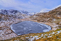 Frozen Llyn Teyrn with Y Llewydd and Mount Snowdon in background. View west from Miner&#39;s Track. Snowdonia National Park, Gwynedd, Wales, UK. March 2018.