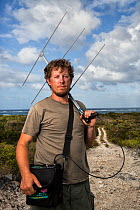 Portrait of scientist Nathan Cooper holding radio-telemetry equipment to track Kirtland&#39;s warbler (Setophaga kirtlandii). Cat Island, Bahamas. April 2017.