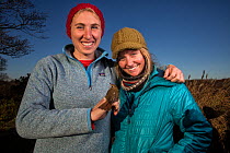 Biologist Clara Cooper-Mullin (left) and her colleague Olivia DaRugna. Clara is holding a Hermit thrush (Catharus guttatus), as part of her study into the migration behaviour of birds that use the isl...