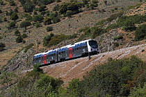 Trinicellu train running along hillside on a metre gauge track, Corsica, France. May 2017.
