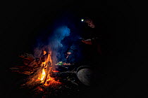Researchers keeping warm by a fire next to the Mitta Mitta river, whilst monitoring gill nets which have been placed in the river to capture Platypus (Ornithornychus anatinus). Mitta Mitta River, Dart...
