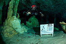 Scuba diver next to the Cavern Limits sign, with picture of the grim reaper. Near Tulum, Quintana Roo, Yucatan Peninsula, Mexico.