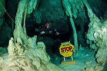 Scuba diver on the &#39;CAVERN LIMITS Stop&#39; sign marks the limit of the cavern zone and should not be passed. Gran Cenote, near Tulum, Quintana Roo, Yucatan Peninsula, Mexico.