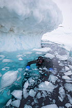 Photographer Franco Banfi beside iceberg before diving under ice. Tasiilaq, East Greenland. April 2018.
