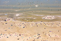 People on beach and in shallow sea. Parnu, the summer capital of Estonia. Parnumaa, Western Estonia. July 2010.