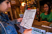 Person looking at menu at Kawaramati Cat Cafe Kyoto, Japan