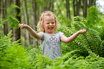 Girl exploring amongsts ferns during forest kindergarten session. Aberdeen, Aberdeenshire, Scotland, UK. Editorial use only