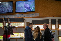 Visitors at Loch Garten Osprey Centre with live Osprey (Pandion haliaetus) footage on screens. Boat of Garten, Cairngorms National Park, Scotland, UK.