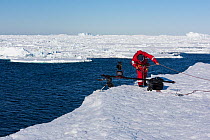Camerman Lindsay McCrae preparing to film on ice shelf overlooking Southern Ocean during summer , for BBC Dynasties Penguin programme. Atka Bay, Antarctica. October 2017.. Atka Bay, Antarctica. Februa...