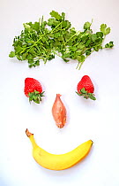 Smiling face made from parsley, strawberries, shallots and a banana.