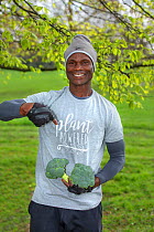 Vegan man holding broccoli, wearing a &#39;plant powered&#39; t-shirt. North London, England, UK. March 2019.