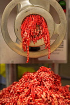 Beef going through mincing machine at butchers.