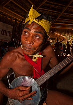 Man of the Batak indigenous tribe playing a stringed instrument in the Batak Visitors Centre at Barangay Concepcion, Puerto Princesa, Palawan, the Philippines.