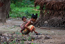 A Batak woman with her child in a sling sharpening a knife in Sitio Kalakwasan in Cleopatra&#39;s Needle Critical Habitat, Palawan, the Philippines.
