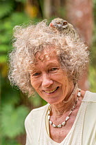 Wildlife carer Margit Cianelli with a Green ringtail possum (Pseudochirops archeri) baby on her head. Atherton Tablelands, Queensland, Australia. Model released.