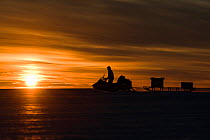 BBC cameraman riding skidoo across ice at sunset. Atka Bay, Antarctica. February 2017.