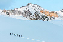 A group of mountaineers climbing to go skiing across the mountains from Valnontey to Valsavarenche in spring, Gran Paradiso National Park, Aosta Valley, Italy, April
