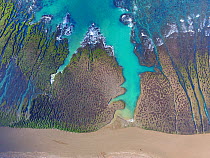 Aerial view of Atlantic ocean with channels through algae covered rock. Punta Norte, Valdez Peninsula, Argentina. May 2019.