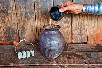 Kayan Lahwi woman adding hot water to a liquor distilled from fermented sorghum, a very common drink among Kayan peasants. The dried yeast balls (left) are used to make this liquor. The Long Neck Kaya...