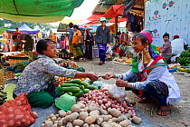 Kayan Lahwi woman with brass neck coils and traditional clothing buying potatoes at the market. The Long Neck Kayan (also called Padaung in Burmese) are a sub-group of the Karen ethnic people from Bur...