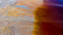 Aerial shot of the shore of an artificial lake polluted by extractive pyrite mining, the orange color comes from sulfite and the blue is a reflection of the sky, Minas de Riotinto, Andalusia, Spain, J...