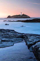 Godrevy lighthouse and rockpool, high tide at sunset, Gwithian, Cornwall, UK. October 2018.
