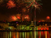 New Years Eve fireworks celebration in Reykjavik, Iceland, with lights reflected in the water