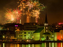 RF - New Years Eve fireworks celebration in Reykjavik, Iceland, with lights reflected in the water (This image may be licensed either as rights managed or royalty free.)
