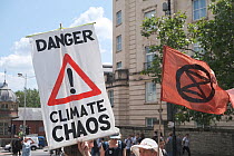 &#39;Danger climate chaos&#39; placard and Extinction Rebellion flag. Climate change protest march, Bristol, England, UK. 16 July 2019.