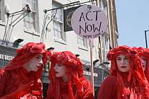 The Red Brigade performance artists with &#39;Act Now with love!&#39; placard. Extinction Rebellion climate change protest, Bristol, England, UK. 16 July 2019.