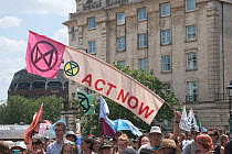 &#39;Act now&#39; banner and Extinction Rebellion flag held aloft during climate change protest march. Bristol, England, UK. 16 July 2019.